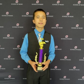 Bryan holding a trophy in front of a UNO banner